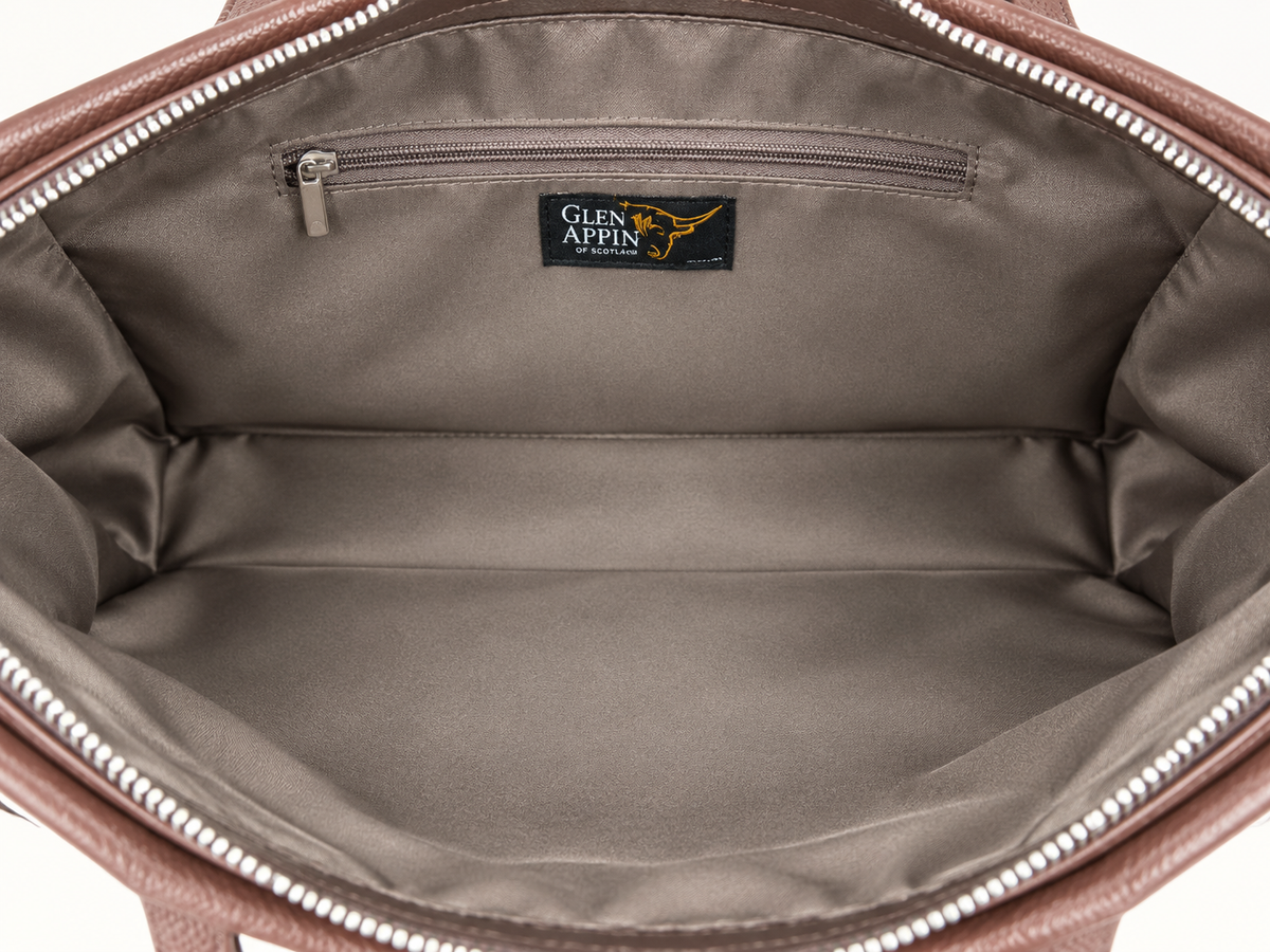 Close-up of the interior of a brown leather bag, showing a spacious zippered compartment lined in taupe-brown fabric with a black Glen Appin brand label stitched inside.