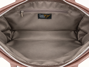 Close-up of the interior of a brown leather bag, showing a spacious zippered compartment lined in taupe-brown fabric with a black Glen Appin brand label stitched inside.